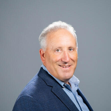 A man in a blue suit against a neutral backdrop