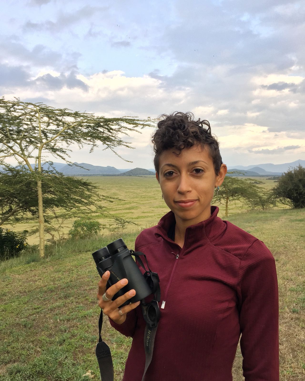 A photo of postdoctoral researcher Christine Wilkonson holding a pair of binoculars.
