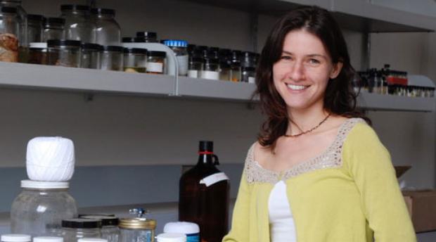 Portrait of Bree Rosenblum standing in a lab in front of glass jars