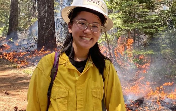 Katie Low stands by a prescribed fire in a forest setting