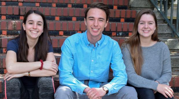 Three students sit on a brick staircase