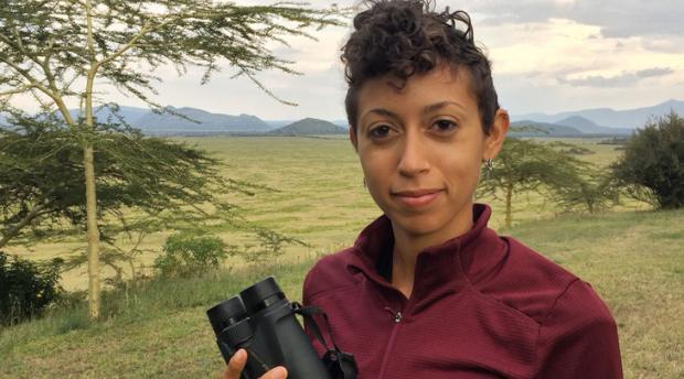 A photo of postdoctoral researcher Christine Wilkinson holding a pair of binoculars.