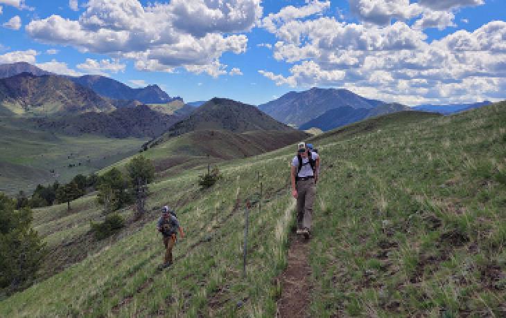 Image of two students walking along a trail in the mountains