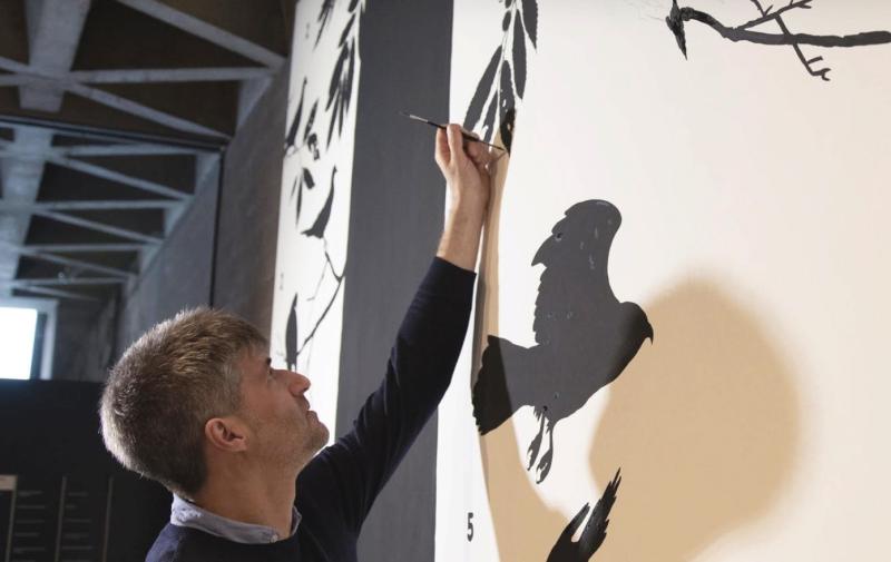 A man painting a bird on a wall